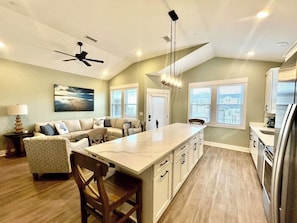 A modern kitchen with a central island, built-in appliances, and a dining area with a sofa and chairs.