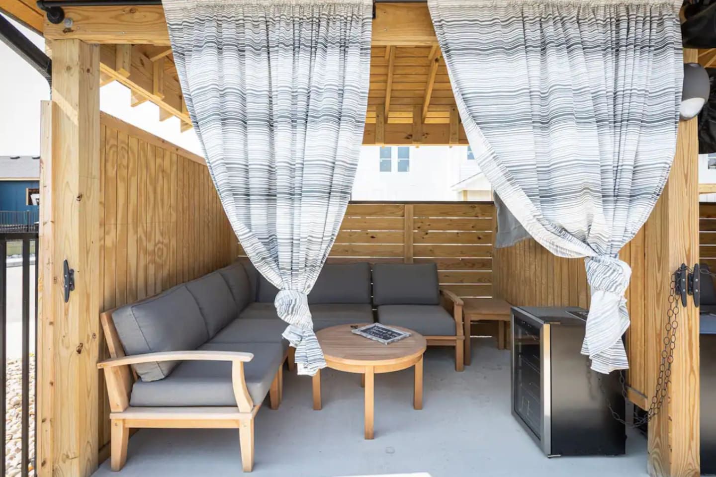 Un espace extérieur aménagé en bois, avec un canapé, des fauteuils et une table.