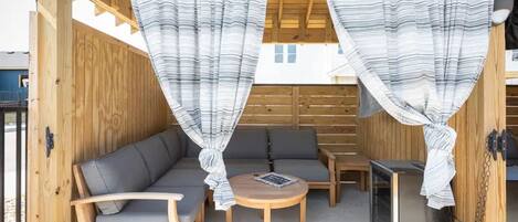Un espace extérieur aménagé en bois, avec un canapé, des fauteuils et une table.
