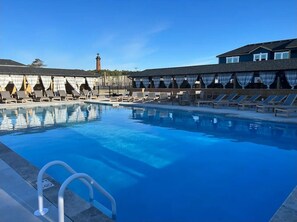 Relax by the pool surrounded by lounge chairs and a picturesque lighthouse view.