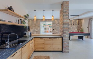 Enjoy cooking in this well-equipped kitchen with a central island, brick accent wall, and modern sink.