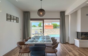 Enjoy meals in this dining area with a glass table and comfortable seating for four, surrounded by a serene outdoor view.