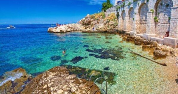 Overlooking the calm sea, this serene coastal scene features a historic stone wall with arches.