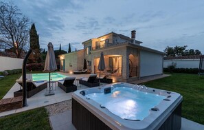 Een tweelaags huis met een zwembad, buitenmeubilair en een jacuzzi.