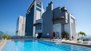 A modern hotel with a rooftop infinity pool, lounge chairs, and a view of the city skyline. - MURANO ELITE  GRADIMAR (Cartagena)