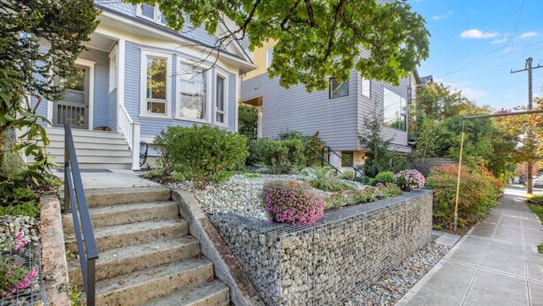 A residential property with a stone retaining wall, a set of stairs leading to a front door, and a well-maintained garden. - Quiet Capitol Hill Bungalow w/ Wi-Fi & Laundry (Seattle)