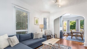 A living room with a sofa, a coffee table, a dining table with chairs, and a fireplace. - Quiet Capitol Hill Bungalow w/ Wi-Fi & Laundry (Seattle)