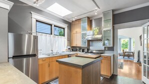 A modern kitchen with a central island, stainless steel appliances, and wooden cabinetry. - Quiet Capitol Hill Bungalow w/ Wi-Fi & Laundry (Seattle)