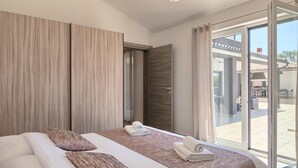 Habitación de hotel moderna con una cama grande, vistas al patio exterior y una puerta corrediza de vidrio.