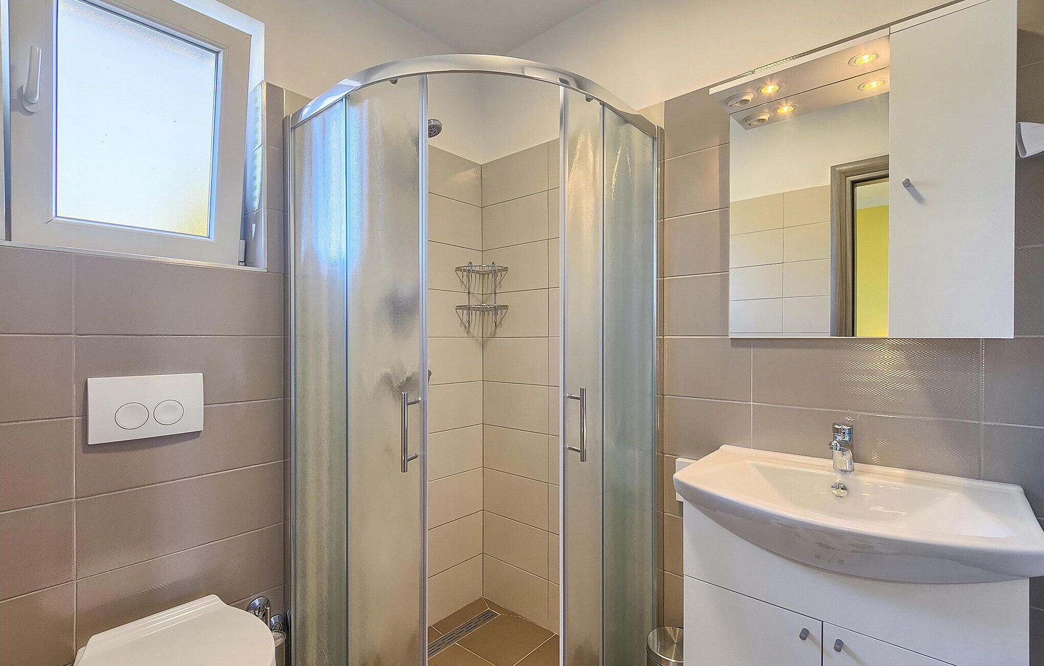 A bathroom with a glass-enclosed shower, a sink, and a mirror above it.