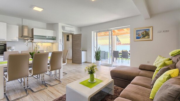 A modern living room with a sofa, a coffee table, and a dining area with chairs and a table.