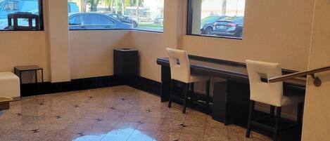 A hotel lobby with a tiled floor, a reception desk, and seating area.