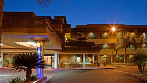 A hotel with a traditional architectural style, featuring multiple balconies and a central courtyard with palm trees. - Hotel Xola (Moreno Valley)