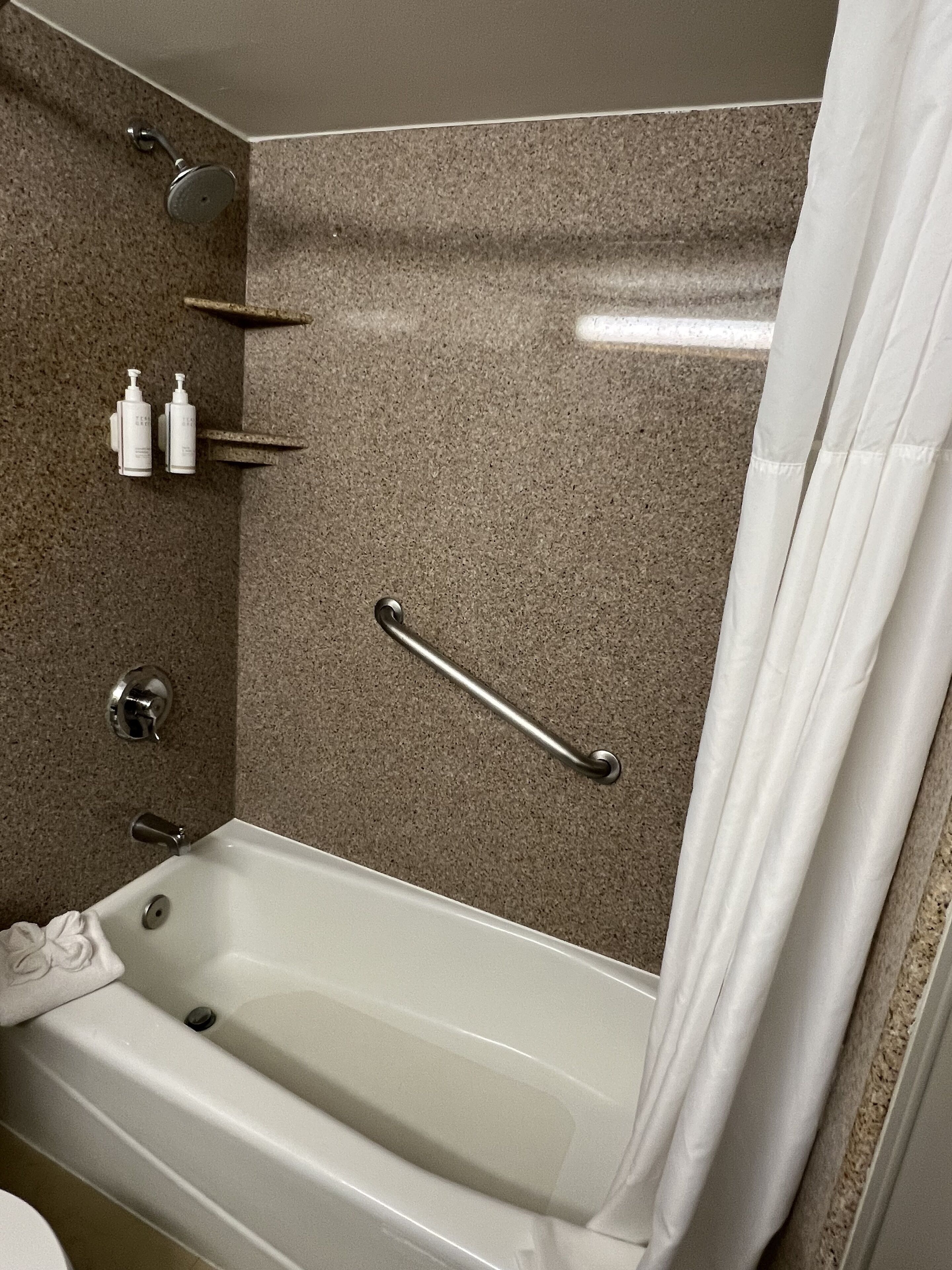 Une salle de bain équipée d’une baignoire, d’une douche et d’une barre d’appui.
