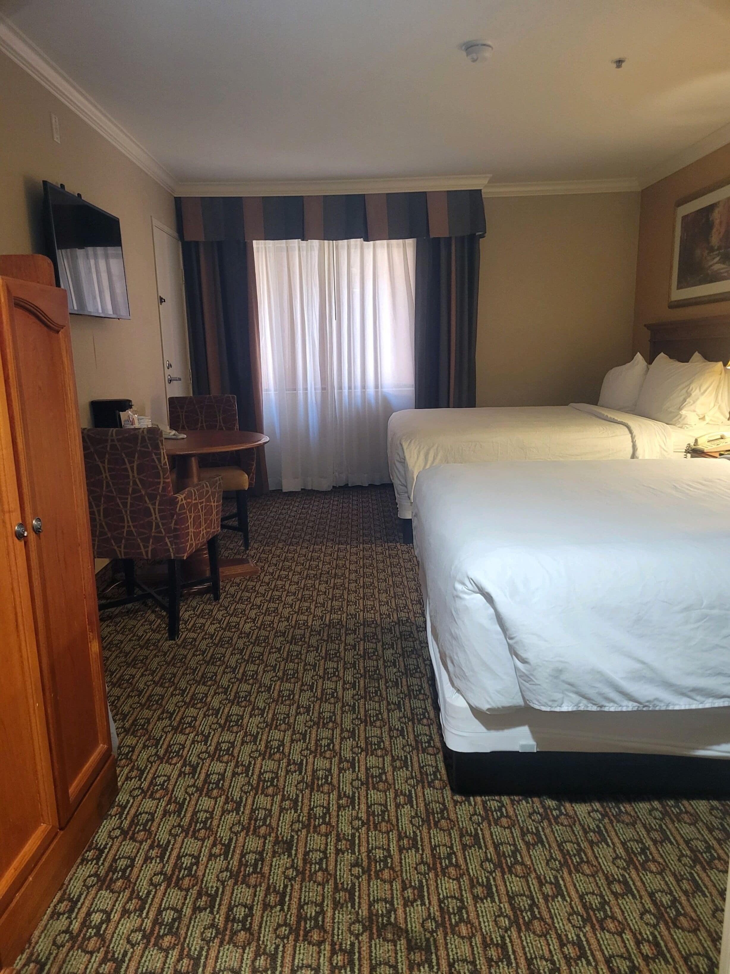 Une chambre d’hôtel avec deux lits, un bureau et une chaise.