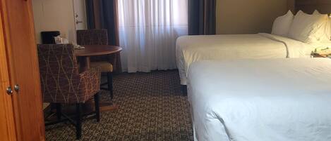 Habitación de hotel con dos camas, un escritorio y una silla.