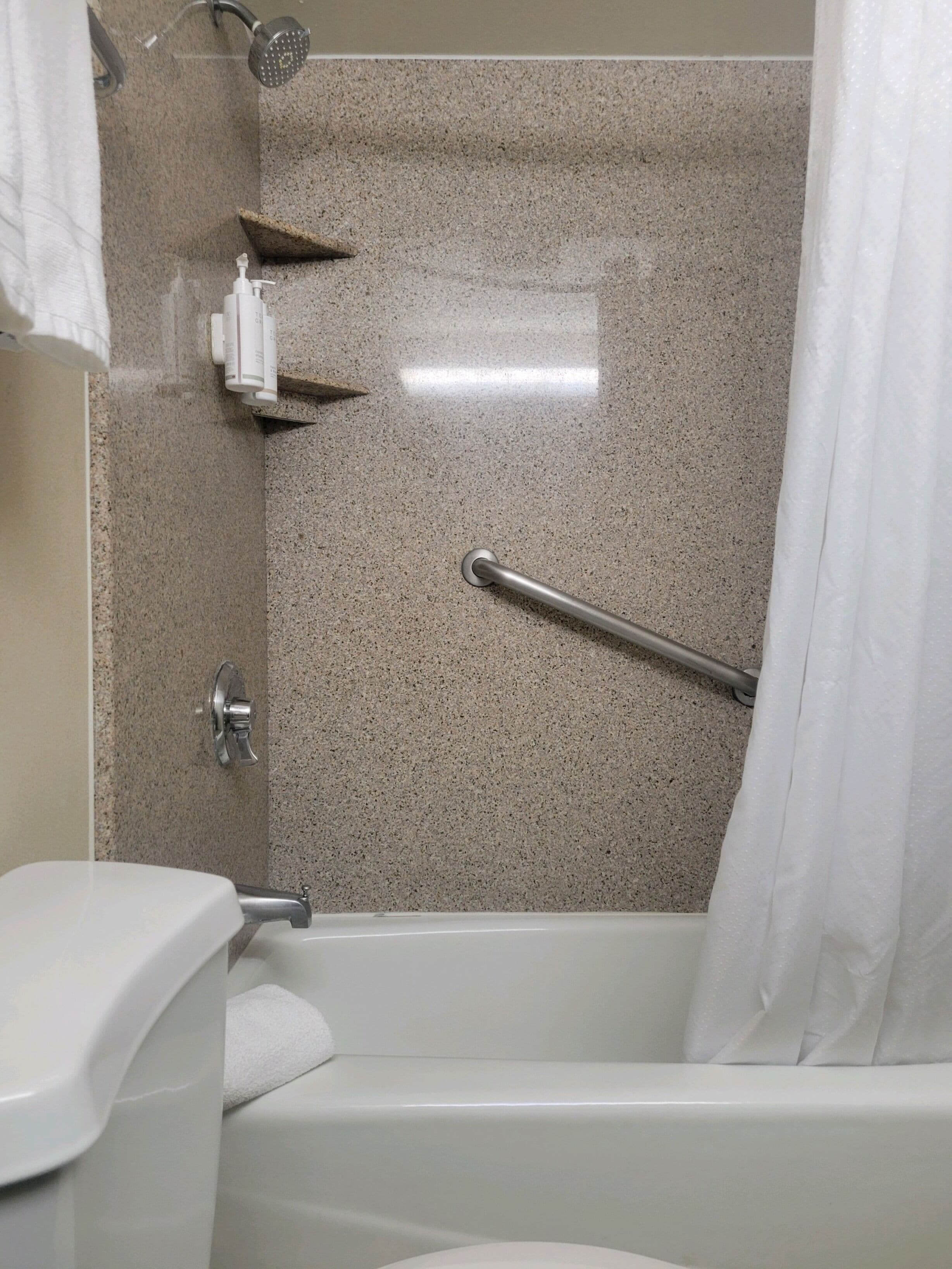 A bathroom with a shower, toilet, and a towel rack.