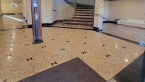 A spacious lobby with a marble floor, a handrail, and a staircase leading to upper floors. - Hotel Xola (Moreno Valley)