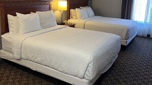 A hotel room with two beds, a nightstand with a lamp, and two framed pictures on the wall. - Hotel Xola (Moreno Valley)