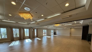 A spacious, well-lit room with large windows, a chandelier, and a tiled floor. - Hotel Xola (Moreno Valley)