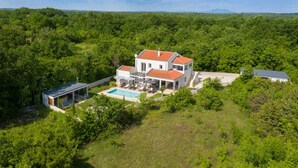 A two-story house with a swimming pool, surrounded by dense greenery and hills in the background. - Nice home in Svetvincenat (Svetvincenat)