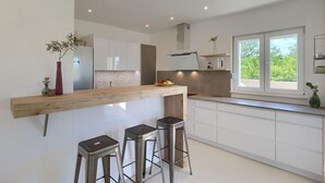 A modern kitchen with a wooden island, white cabinetry, and a large window providing natural light. - Nice home in Svetvincenat (Svetvincenat)