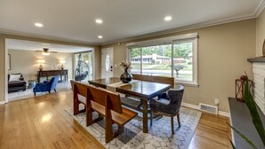 A spacious dining area with a wooden table and benches, large windows with a view of the outdoors, and a ceiling fan. - Quiet Comfort: 5 BR & 2.5 BA, 6 TVs, Pet Friendly (Radcliff)