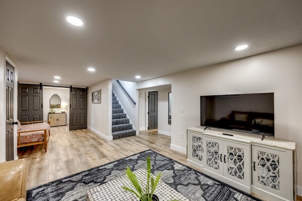 A spacious living area with a large TV, a staircase, and a dining area.