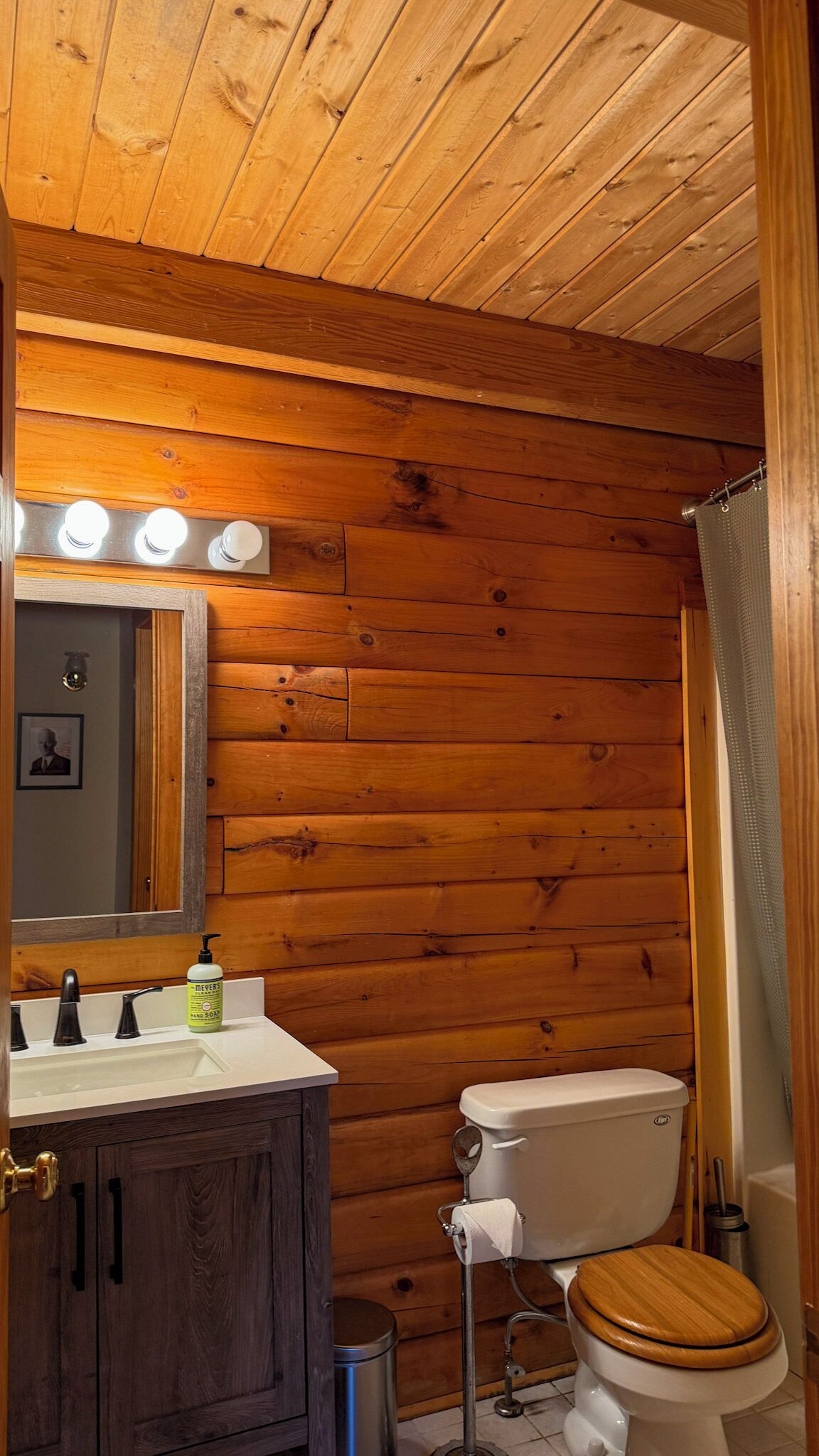 Un baño con paneles de madera, un inodoro, un lavabo y un espejo.