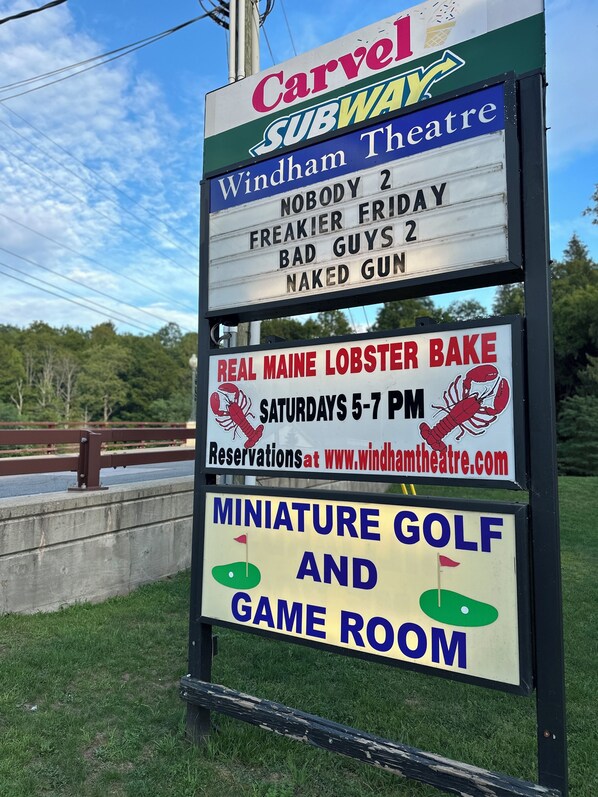 A signboard with various advertisements including a Carvel Subway, Windham Theatre, Real Maine Lobster Bake, and Miniature Golf and Game Room.