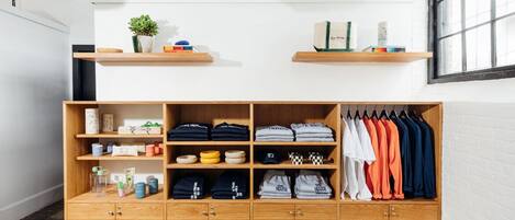 A wooden wardrobe with multiple shelves and drawers, containing folded clothes, hats, and small items.