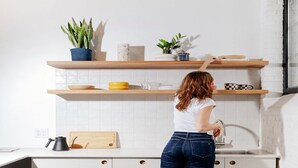 A woman in a kitchen with white cabinets, a wooden countertop, and a sink. - Dye House (Providence)