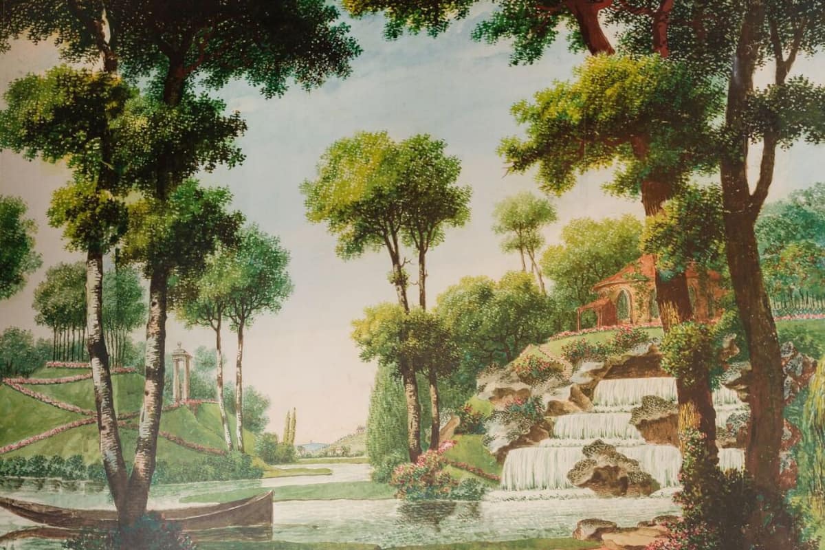 A room with a mural of a landscape, two black chairs, a white table with a vase and books, and a wooden panel wall.