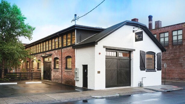 A building with a white facade, large windows, and a garage door. - Dye House (Providence)
