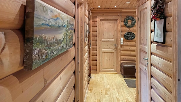 A wooden hallway with a painting on the left, a door at the end, and a bench on the right. - Cozy home in østby with WiFi (Østby)