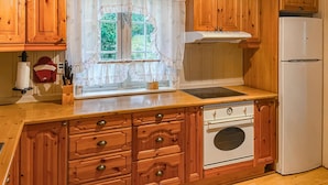 A kitchen with wooden cabinets, a white refrigerator, a stove, and a window with curtains. - Cozy home in østby with WiFi (Østby)