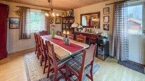 A dining room with a long wooden table, red chairs, a chandelier, and a large window with curtains. - Cozy home in østby with WiFi (Østby)