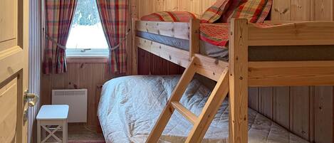 A wooden bunk bed room with a window, a small table, and plaid curtains.