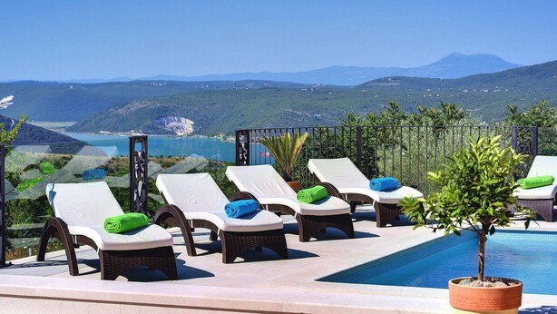 A poolside area with lounge chairs and a view of a mountainous landscape.