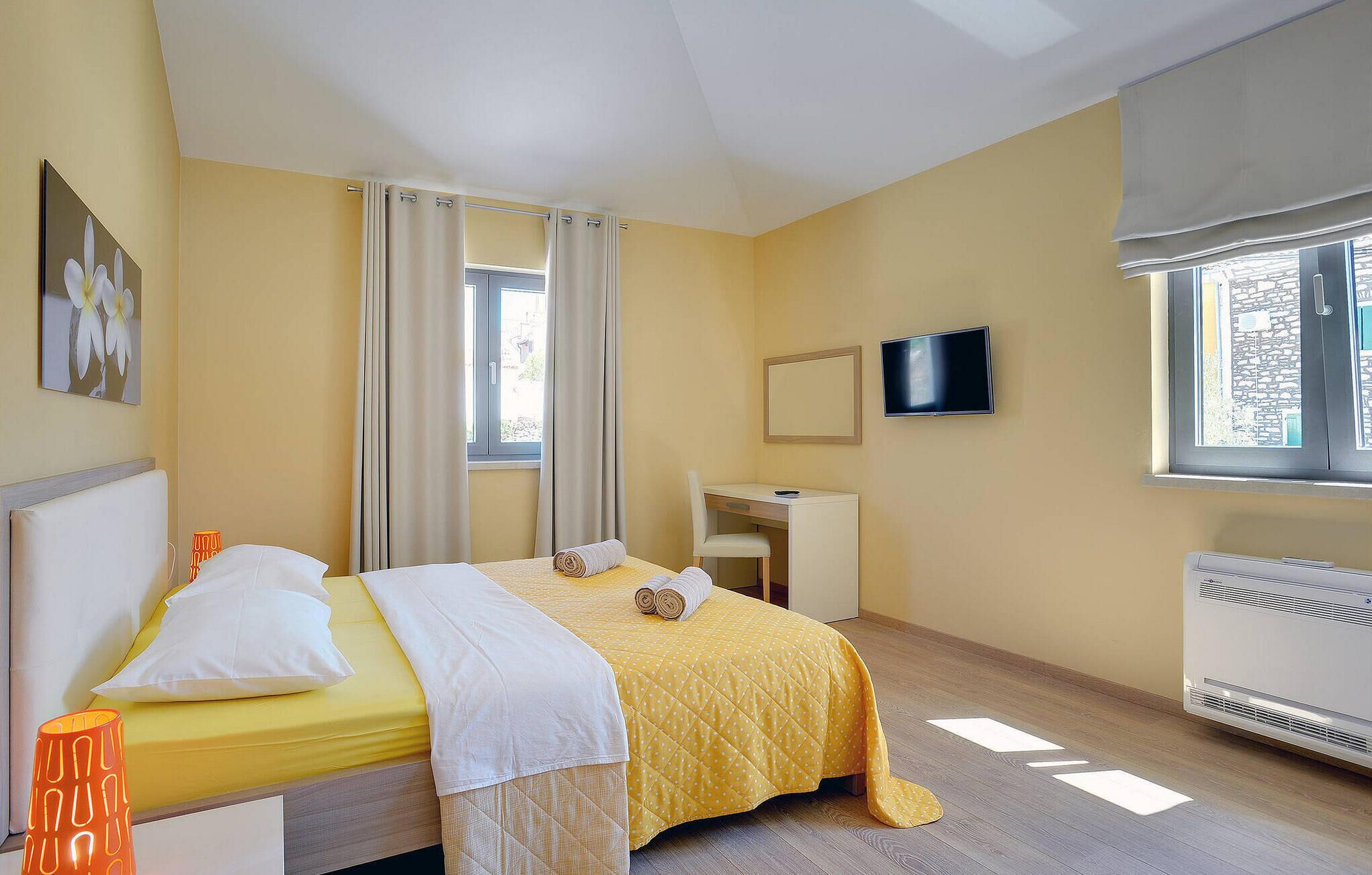 Une chambre d’hôtel avec un lit, un bureau, une télévision et une fenêtre.