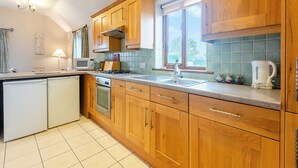 Een keuken met houten kastjes, een magnetron, een fornuis, een spoelbak en een waterkoker.