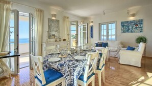 A dining area with a round table set for four, surrounded by white chairs with blue cushions.