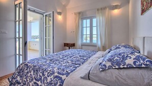 A bedroom with a bed, a window, and a door leading to a balcony.