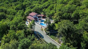 Ein zweistöckiges Haus mit Swimmingpool, umgeben von dichtem Wald.