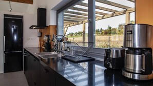 Una cocina moderna con un amplio ventanal, una cafetera y un hervidor.