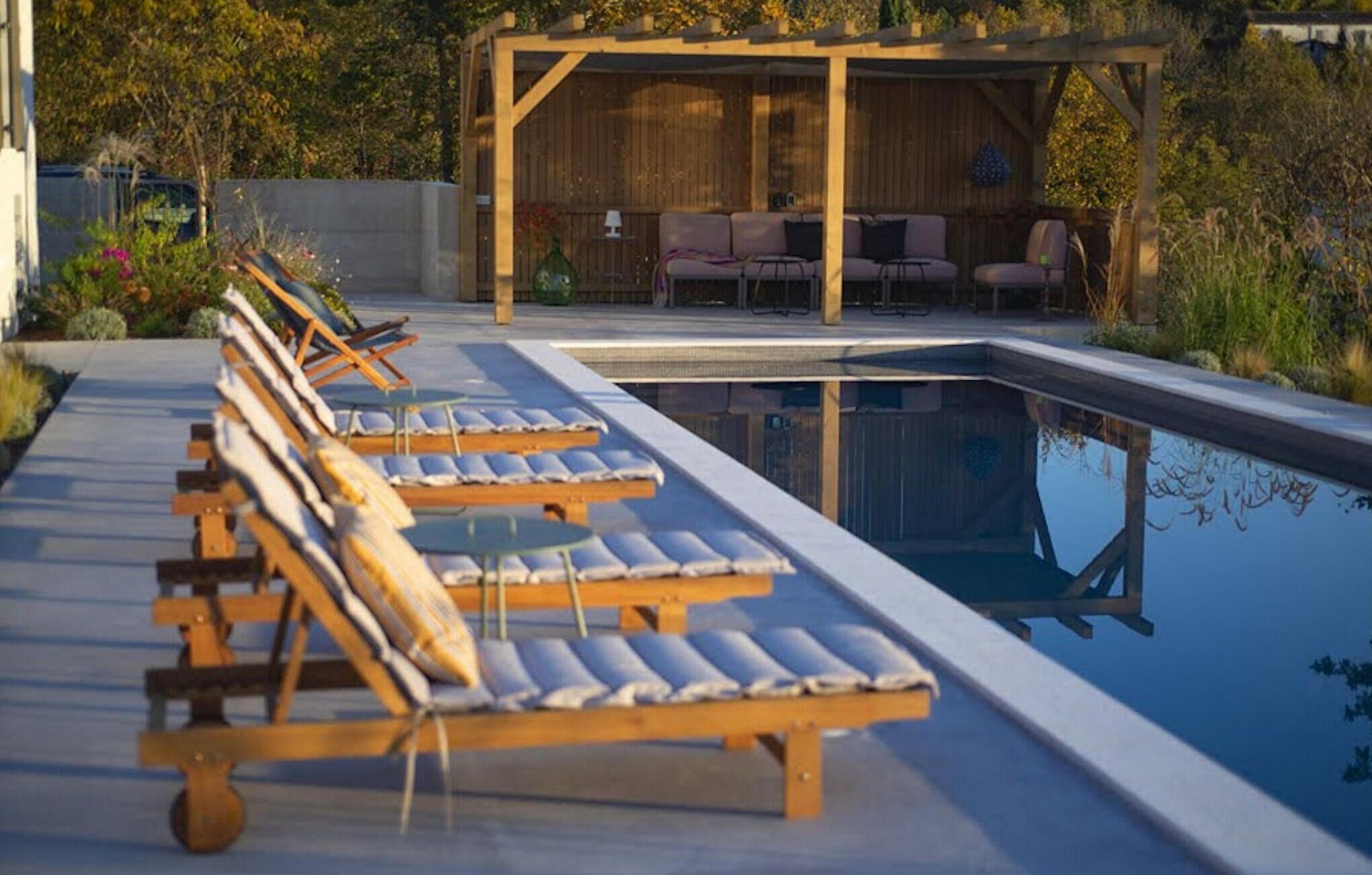Un espace aménagé au bord de la piscine, avec des chaises longues et un coin salon abrité.
