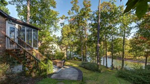 A house with a glass door, a wooden staircase, and a pond in the backyard. - Hilton Lake Getaway w/ Hot Tub & Two Fire Pits (Chapin)