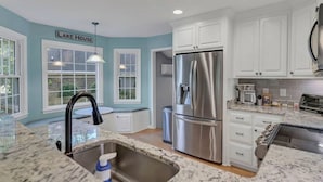 A modern kitchen with white cabinets, stainless steel appliances, and a granite countertop. - Hilton Lake Getaway w/ Hot Tub & Two Fire Pits (Chapin)