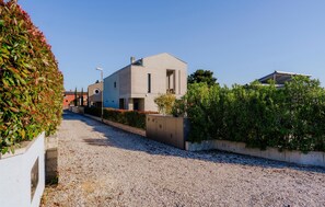 Un bâtiment moderne avec une allée en gravier et une haie bien entretenue.