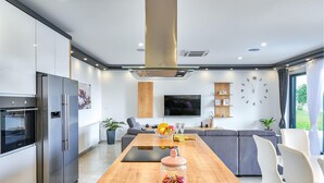 A modern kitchen with a wooden dining table, a built-in oven, and a large refrigerator.